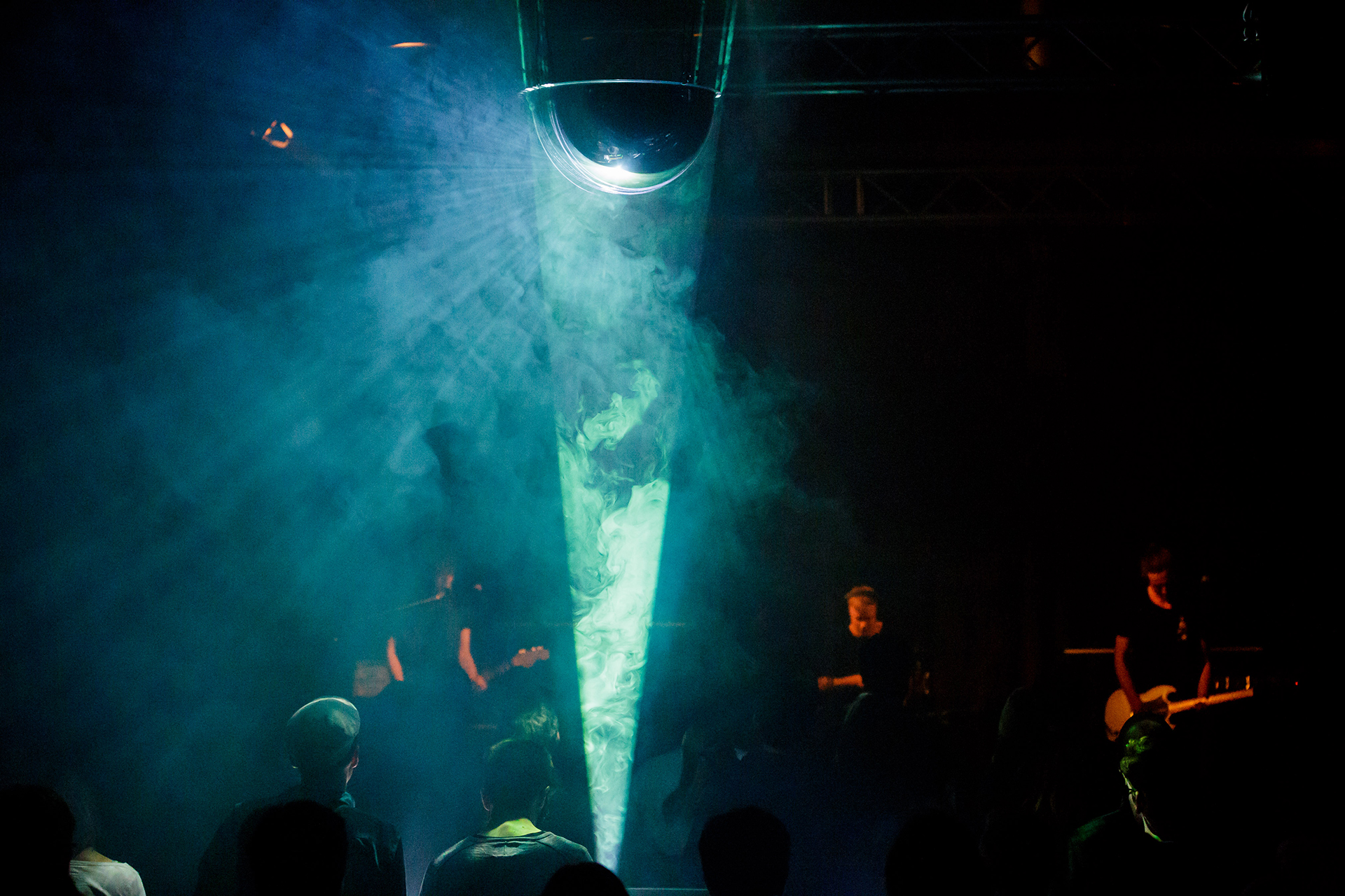 Turquoise light beam from a mirrored dome cutting through fog in front of the band