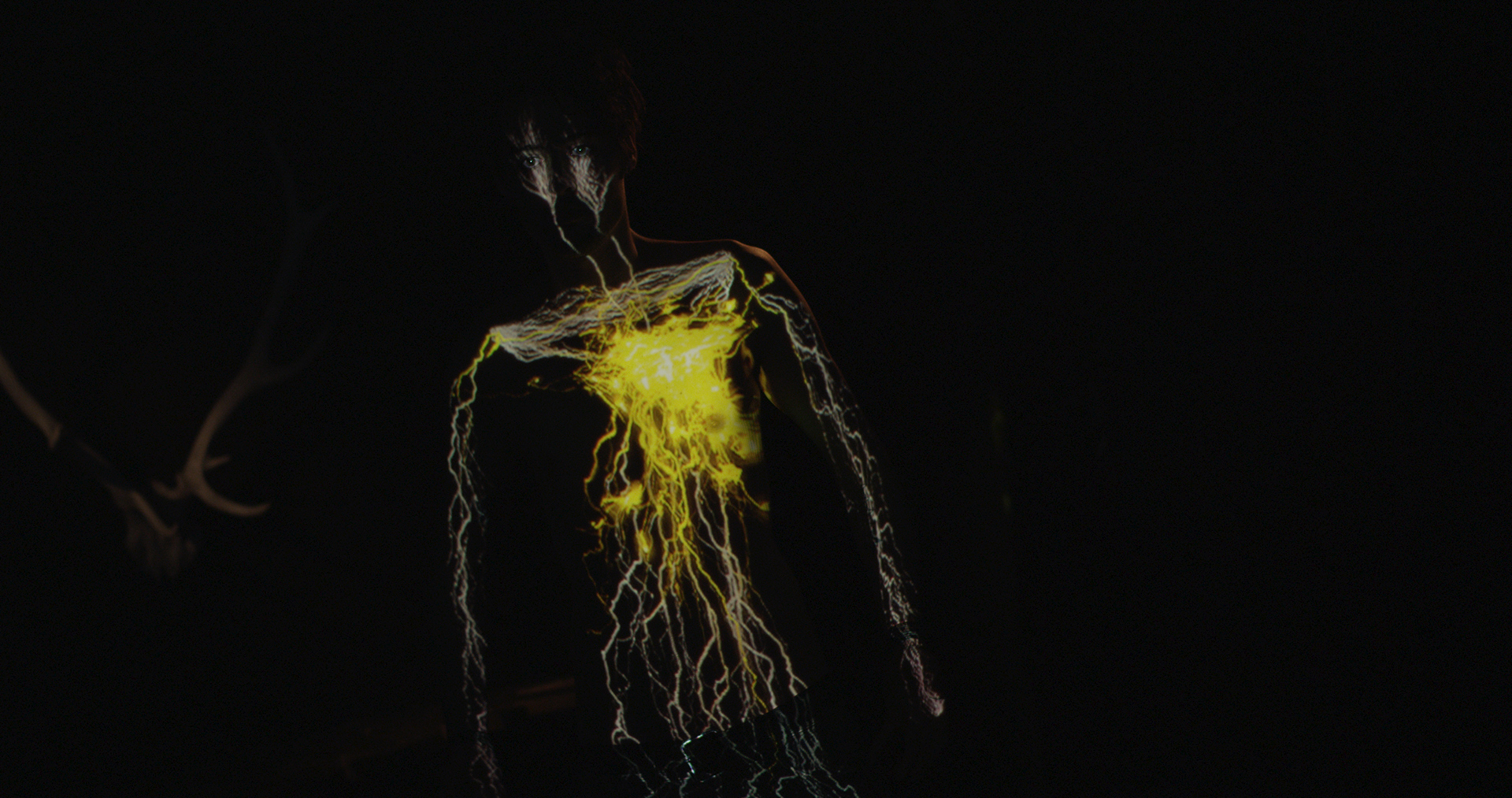 Golden leuchtende Adern als Projektion auf der Brust von Eau-Rouge-Sänger Jonas, Still aus dem Musikvideo „Golden Nights“