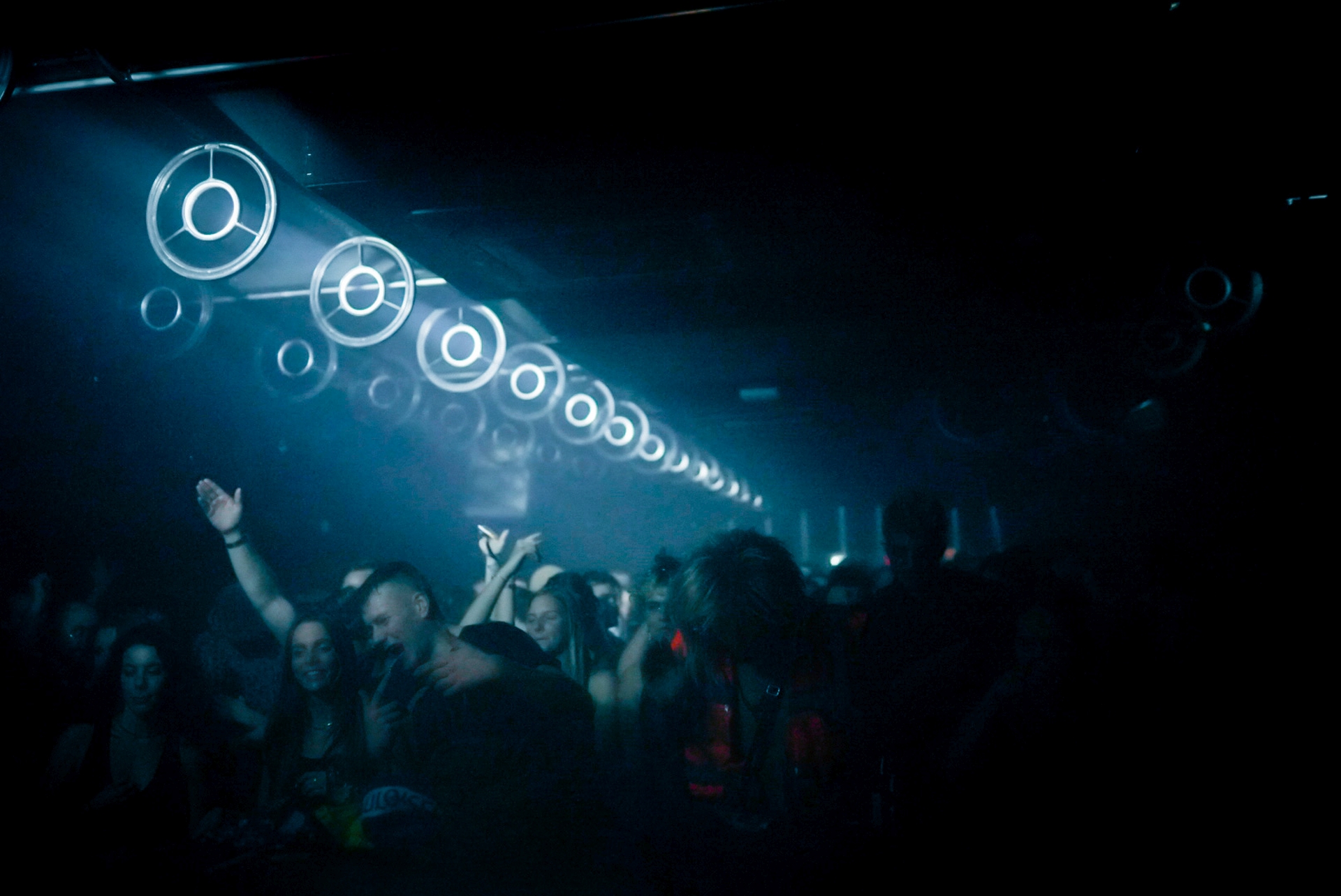 Blue-lit ring fixtures across the ceiling above a cheering crowd at Fridas Pier, Stuttgart