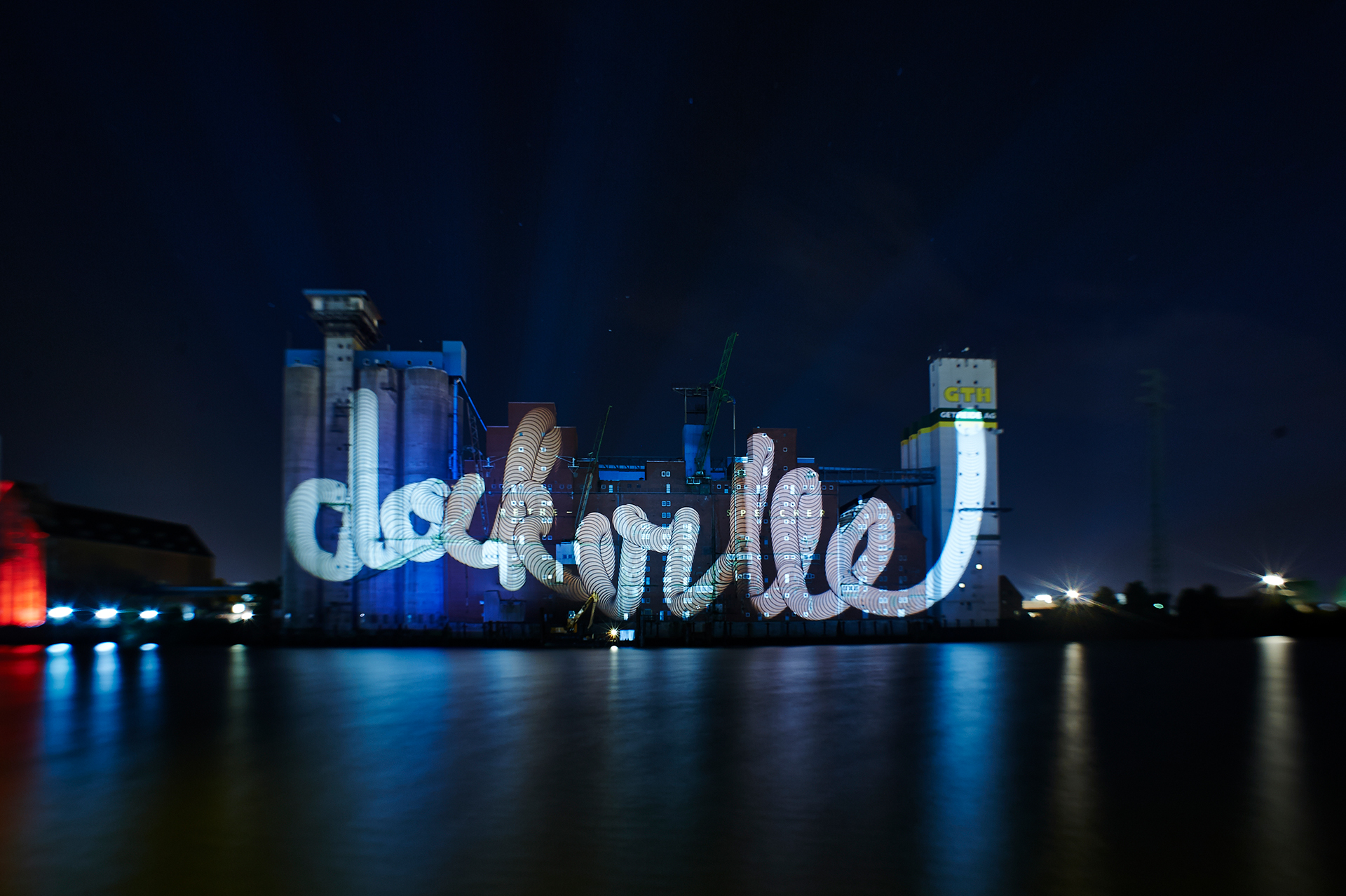White looping "dockville" script lettering projected across the Rethespeicher at night