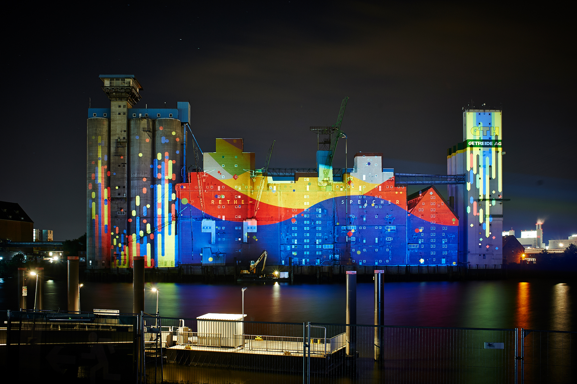 Red, yellow and blue waves with falling coloured drops projected onto the Rethespeicher