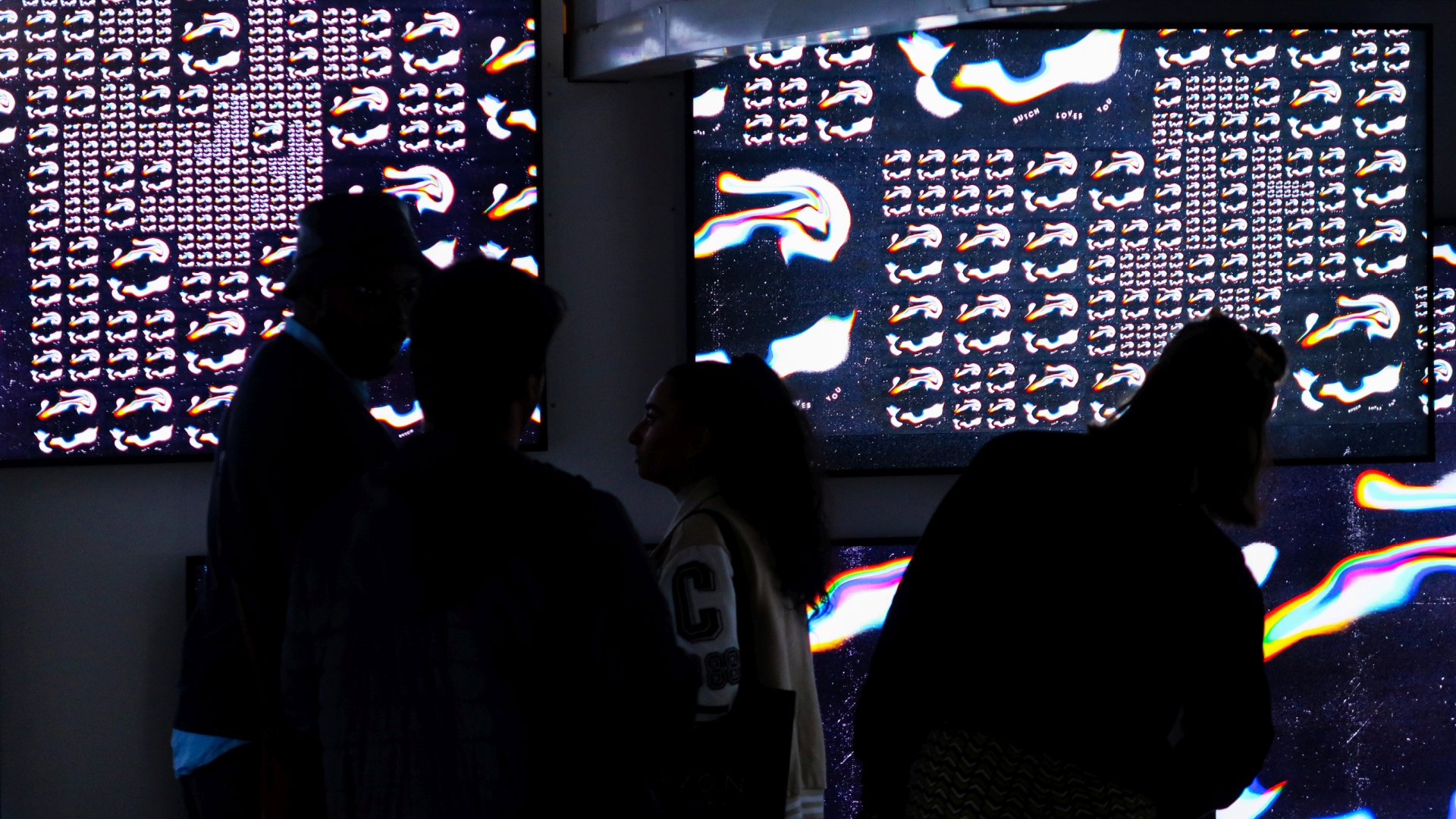 Visitors silhouetted against screens with generatively arranged covers at IN BETWEEN, Reeperbahn Festival 2022