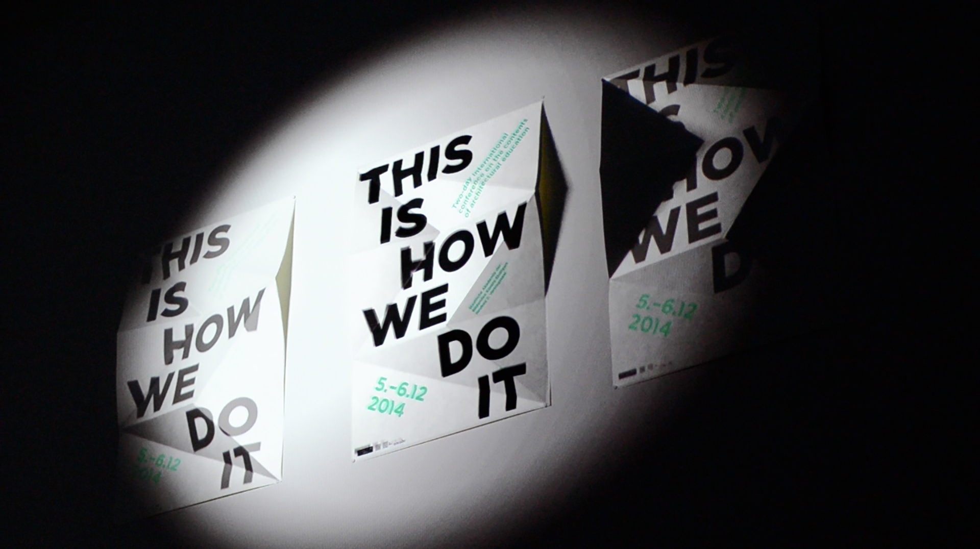 Virtuelles Spotlight wandert über drei gefaltete „This Is How We Do It“-Plakate, Projection Mapping an der ABK Stuttgart